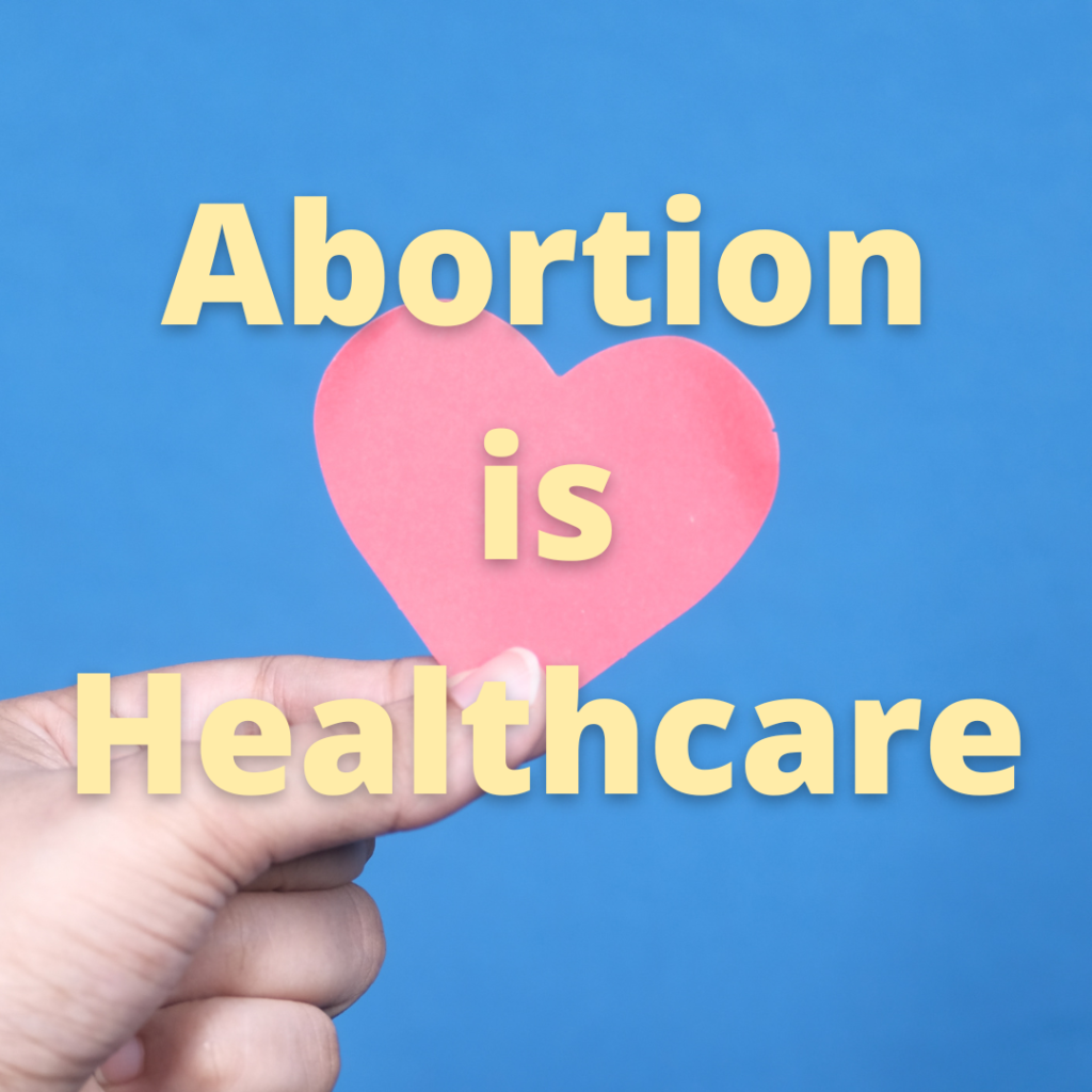 A hand holds a pink paper heart over a bright blue background. Text overlying is yellow, and reads "Abortion is healthcare."